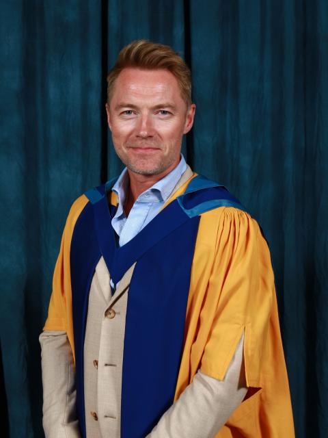 Ronan Keating stands in graduation robes