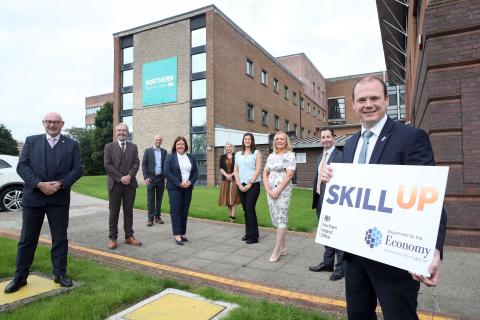 A man holding a sign saying Skill Up and their are a group of people standing behind him