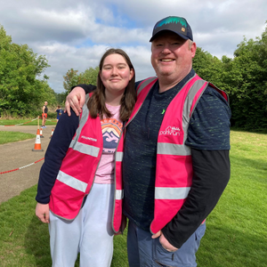 A picture of Stephen Hughes with his daughter by a green field.