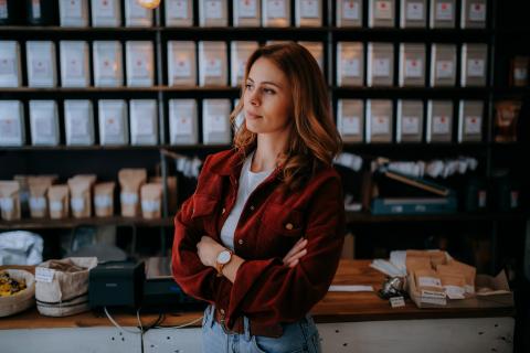 a young woman stand with arms folded in a shop wearing a red jacket