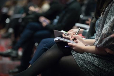 a woman sits writing in a notebook at an event