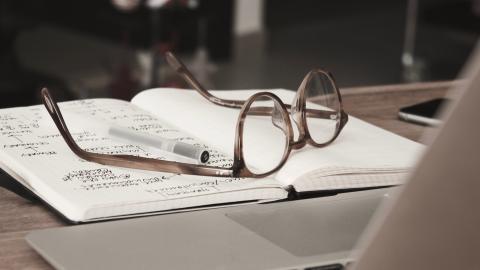 glasses resting on a notebook on a desk