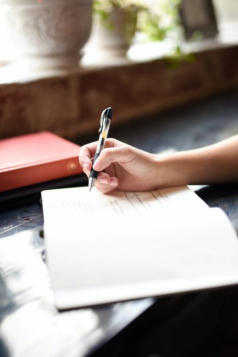 a hand writes in a notebook