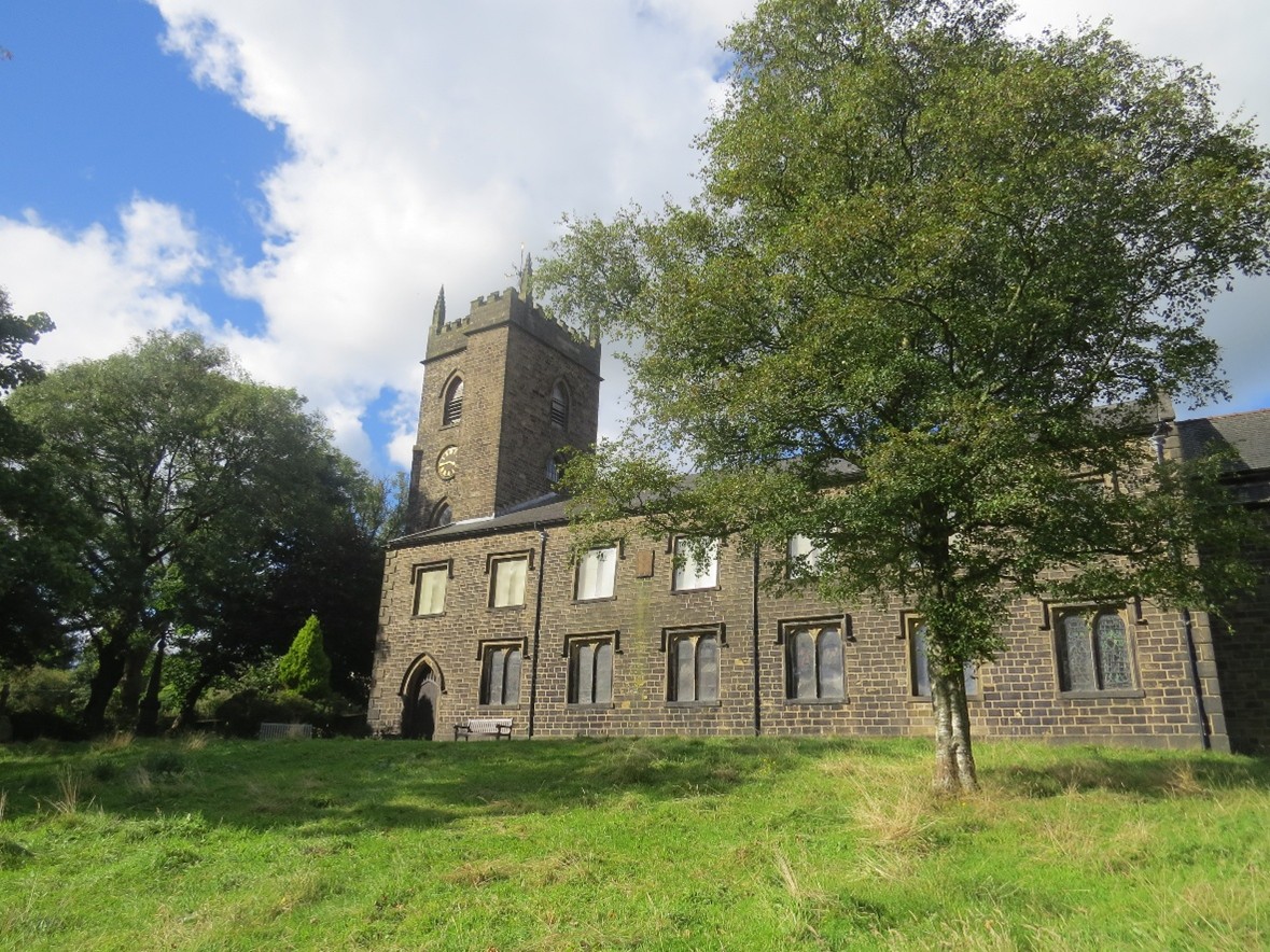 An image of a stone church, with grassy land in the foreground.