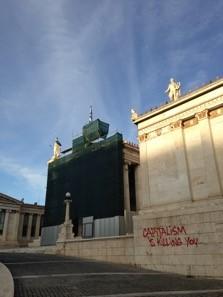Several buildings with grafitti that says 'Capitalism is killing you'.