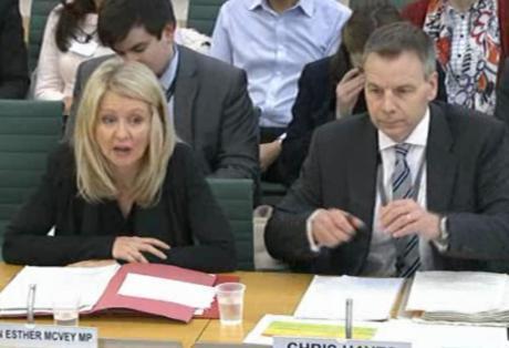 A woman and man sitting at a desk being questioned.