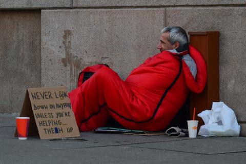 Picture of a homeless man in an orange sleeping bag 
