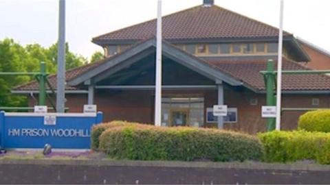 A building that says 'HM Prison Woodhill'.
