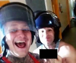 Two white men in police masks smiling and swearing at the camera.