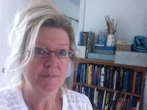 Headshot of a white woman in glasses infront of a bookcase.