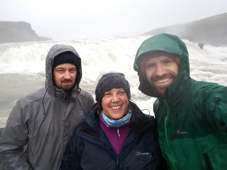 Three people in front of a waterfall