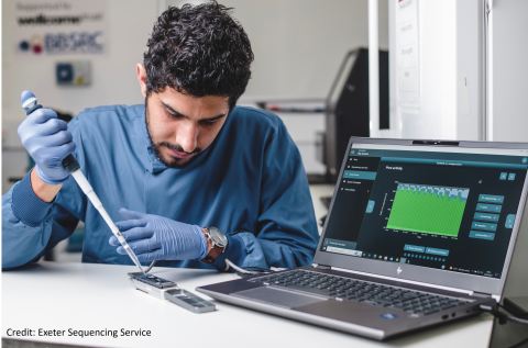 Anthony pipetting on to a device connected to laptop that is displaying the results.