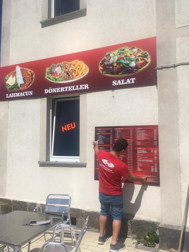 A man works outside a catering establlishment hanging a menu