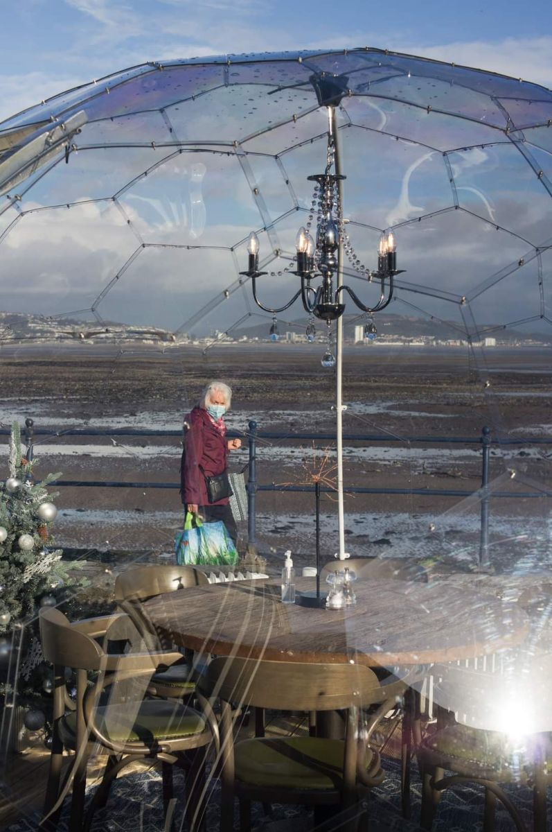 Lady walking past a cafe style lockdown eating out dome