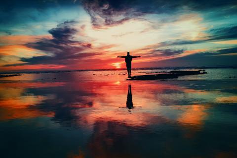 man standing with open arms in the sunset