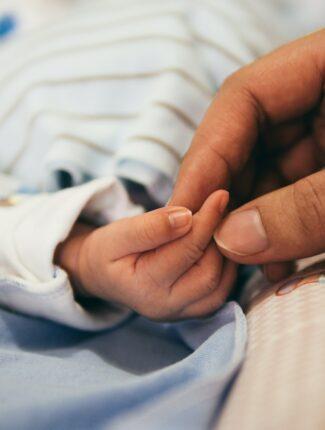 big hand holding new-born baby hand