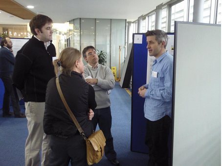 Colleagues gathered around poster presentations at the induction event