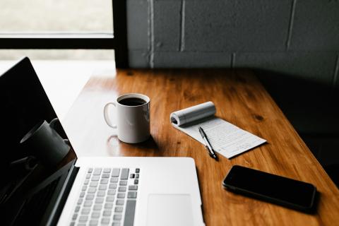 laptop with white mug and black smartphone on table