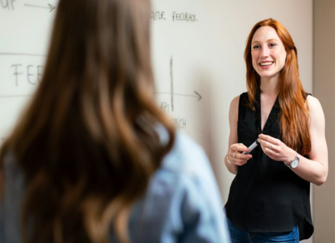 Woman in black top in front of a whiteboard