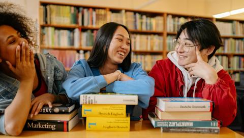Three people smiling with each other in a library
