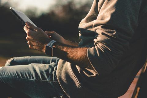 Man reading a tablet outdoors