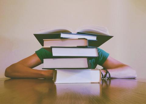 A person hiding behind a pile of books