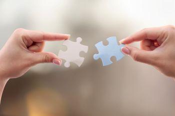 two hands, each holding a jigsaw piece 