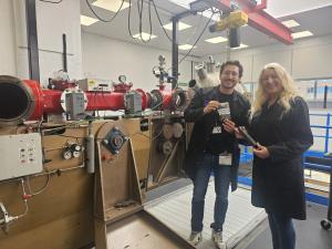 Student Santiago and Dr Jennifer Kingston from Cranfield University standing in front of the Light Gas Gun, showing their samples they have impacted.