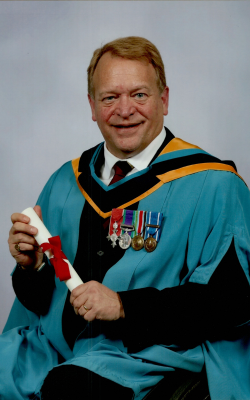 David Dent pictured in his graduation robe and holding a scroll.