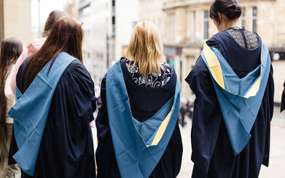 Three gowned graduates, pictured from the back. Photo by Kathryn Tuckerman.