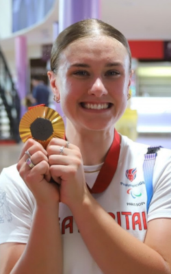 OU graduate Jenny Holl holds up one of her Paralympic cycling gold medals