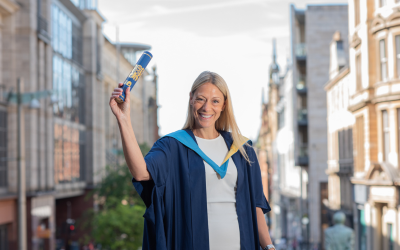 OU graduate Laura Elam in a gown and holding a scroll, on the day of her degree ceremony.