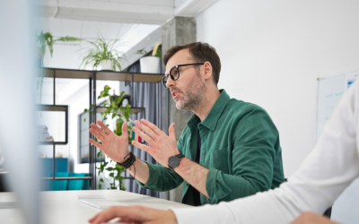 A seated man, talking during a business meeting.