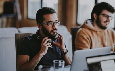 Two people sitting in an office, looking at computer screens