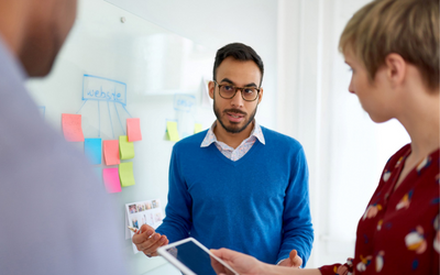 Business people chatting next to a whiteboard. 