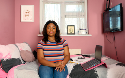 Student Candace, seated next to a laptop, with books and spectacles nearby