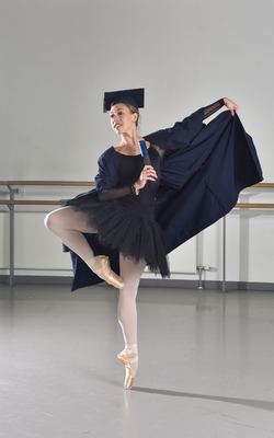 Principal dancer Constance Devernay-Laurence in a graduation gown, holding an OU degree scroll, at Scottish Ballet's studio. Photo by Julie Howden. 