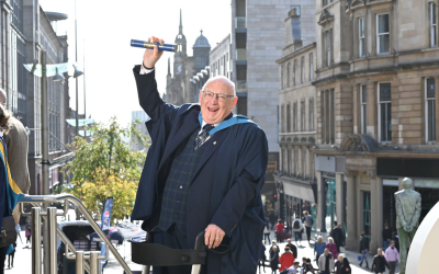 David Torr in his graduation gown and holding a degree scroll. Photo by Julie Howden. 