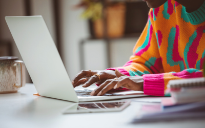 A person in a colourful jumper typing on a laptop