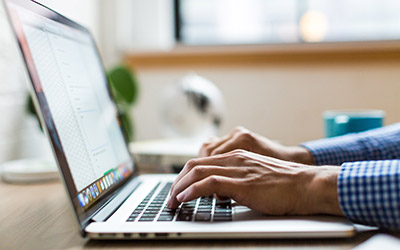 Hands typing on a laptop