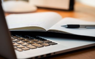 Photo of a laptop and a notebook. 