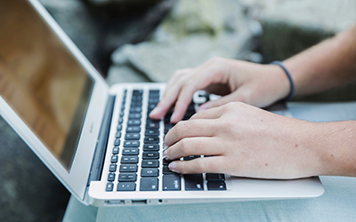 A laptop user's hands resting over the keyboard