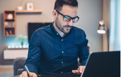   A seated man, looking at his laptop screen