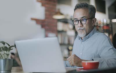 A seated man, looking at his laptop screen