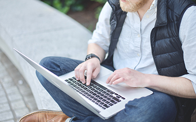 A student sitting outside using a laptop