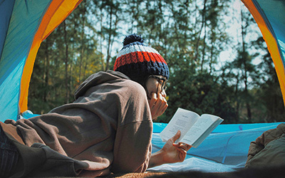 A person lying in a tent, with trees outside