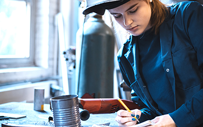 A female welder writing in a notepad