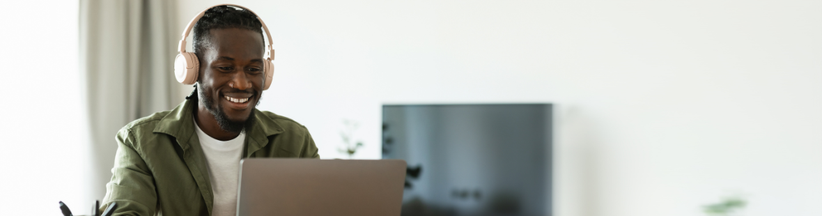 A man wearing headphones and looking at a laptop