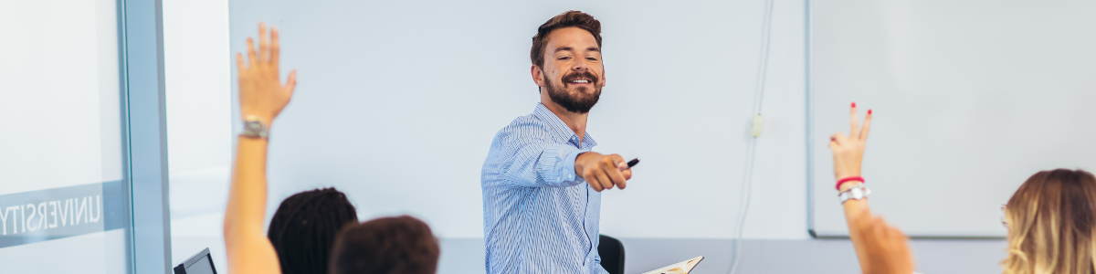 A teacher asking students questions with their hands up
