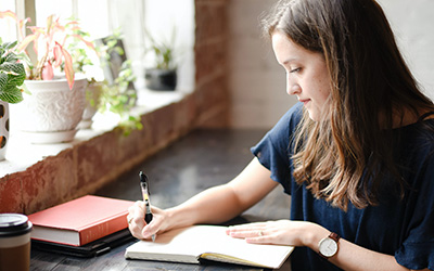 A seated female writing in a notebook